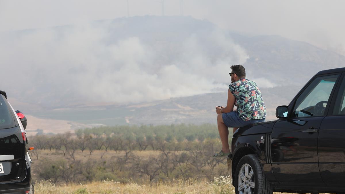 Un joven encaramado a su coche observa impotente el humo del Moncayo.