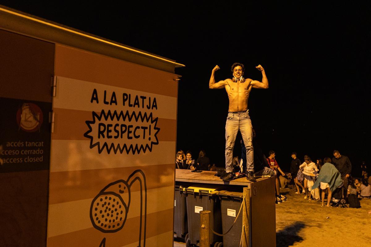 Un chico sobre unos contenedores de basura en la Barceloneta.