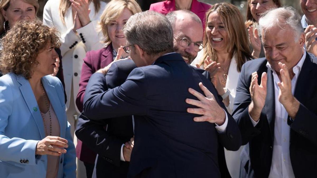 El presidente del PP, Alberto Núñez Feijóo (d), y el presidente del Partido Popular Europeo, Manfred Weber (i) se saludan durante la presentación de Dolors Montserrat como candidata a las europeas. A su lado también Esteban González Pons.