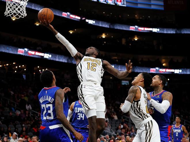 Taurean Prince # 12 de los Atlanta Hawks conduce contra Lou Williams # 23 de los Clippers de LA en State Farm Arena.