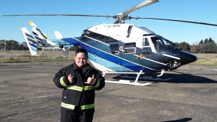 Lafarge posa con el uniforme de bombero y el helicóptero detrás.