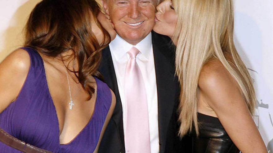 El multimillonario Donald Trump sonríe mientras es besado por dos mujeres. / reuters
