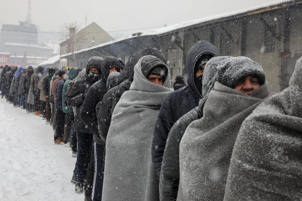 Inmigrantes esperan recibir un plato de comida durante una nevada en Belgrado, Serbia.