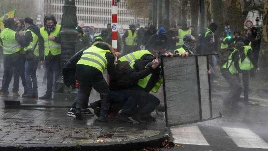 Manifestantes se protegen de los cañones de agua policiales.