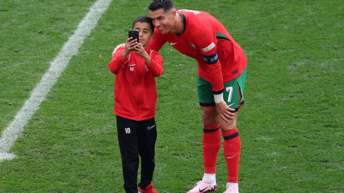 Cristiano Ronaldo se presta a una foto con un niño que saltó al césped.