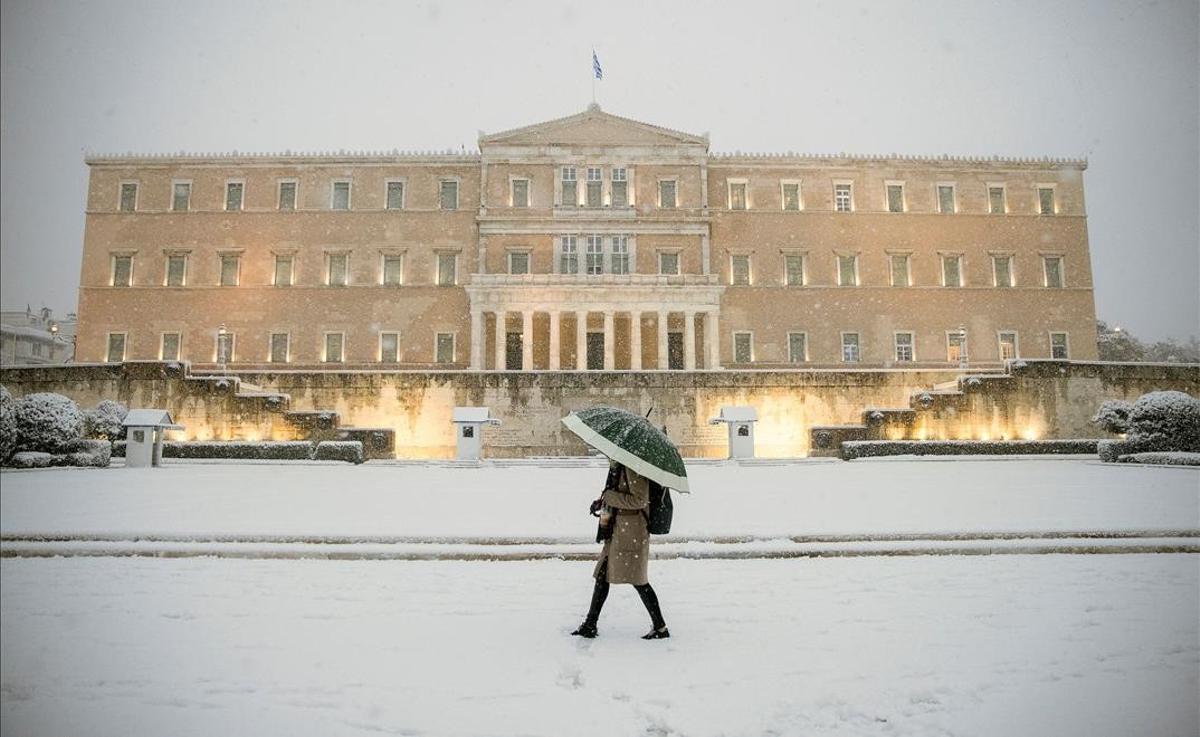 Una mujer pasa delante del parlamento griego, en Atenas, tras la intensa nevada caída en la ciudad.