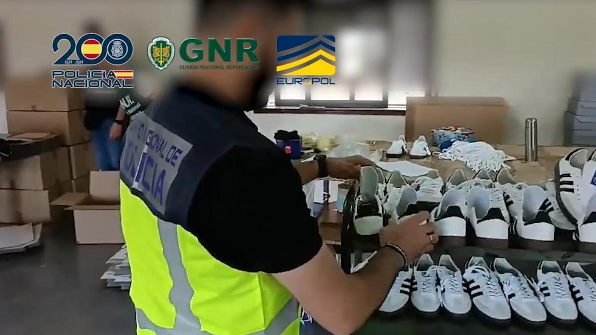 Un agente de la Policía Nacional examina unas zapatillas falsas en un taller de Portugal
