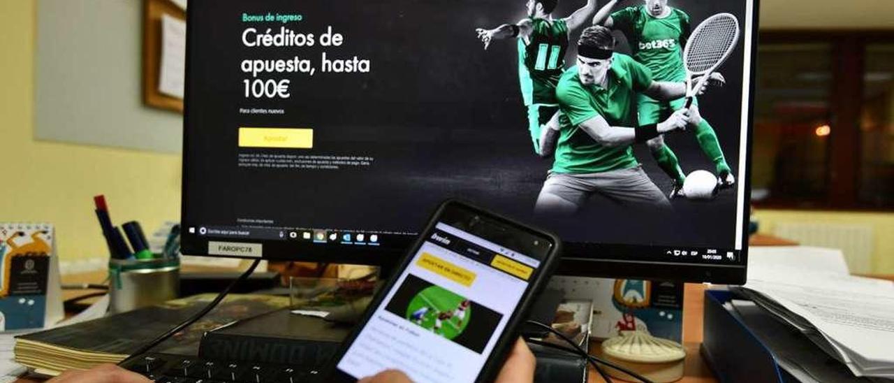 Un joven consulta varias páginas web de apuestas deportivas con su PC y su teléfono móvil. // Gustavo Santos