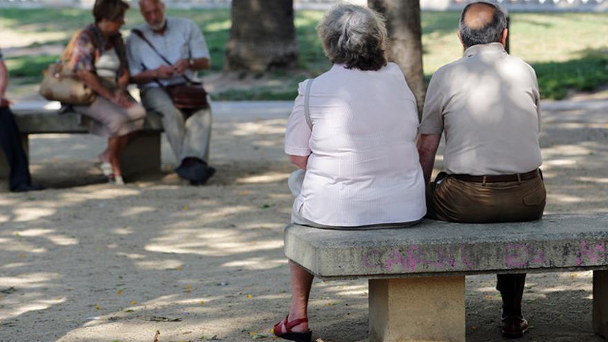 Personas mayores descansan en unos bancos de Barcelona.