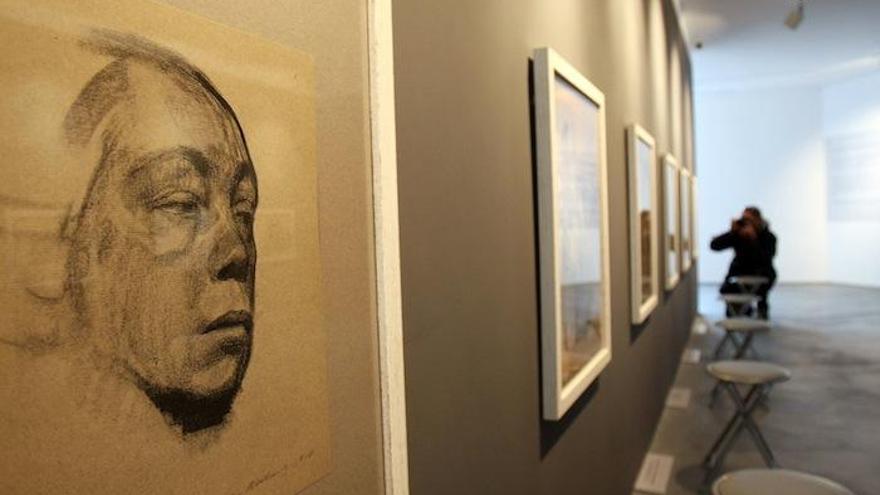 Uno de los dibujos de la expresionista alemana Kollwitz, en primer plano; un periodista observando la muestra.