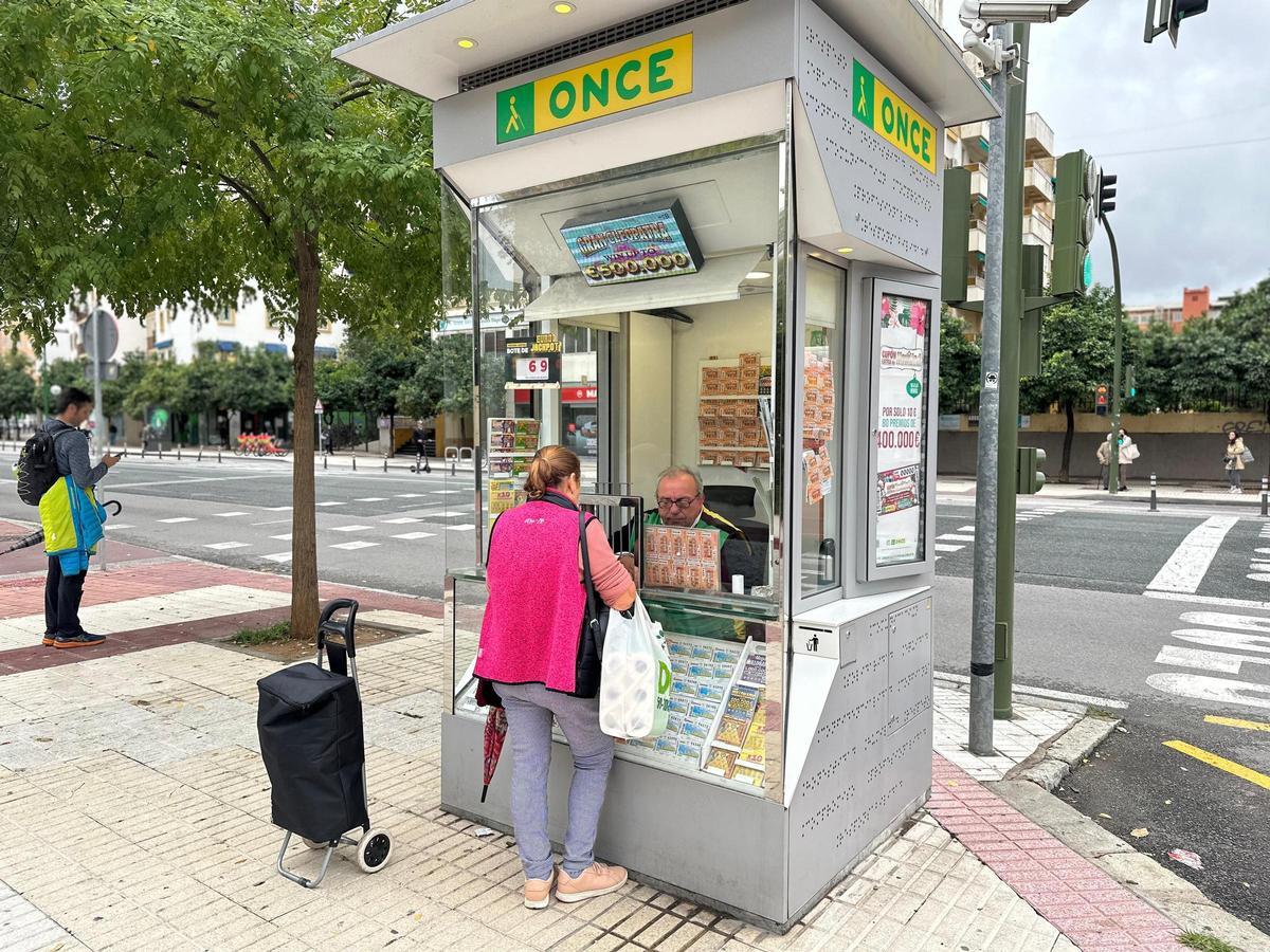 Una vecina habla con Paco González mientras le compra un cupón.