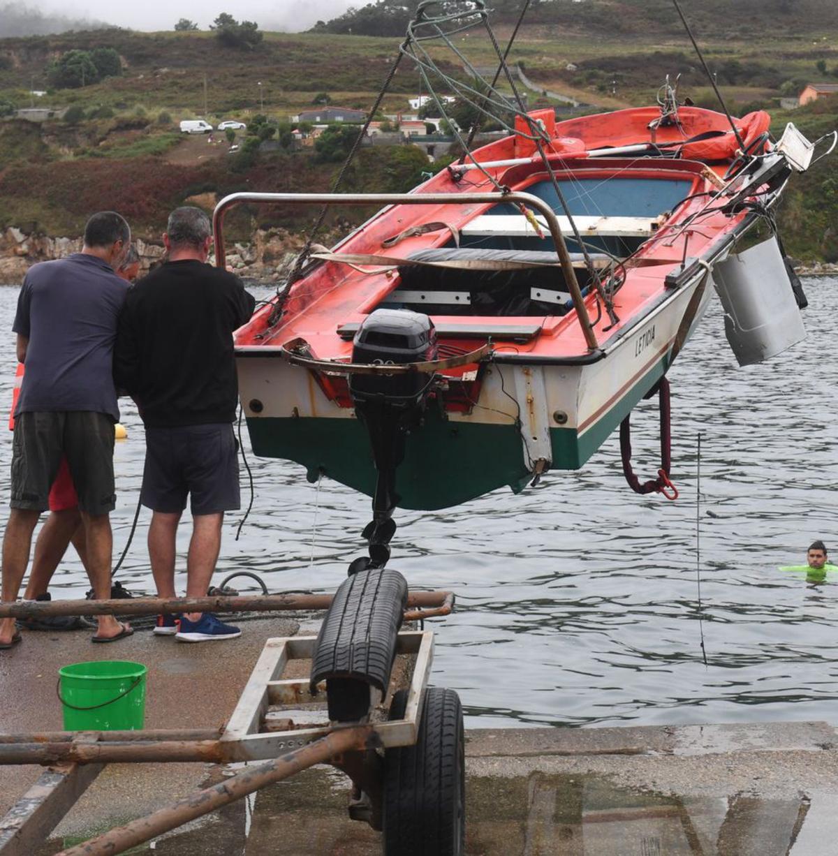 Usuarios de Suevos suben a tierra el bote siniestrado. |   // CARLOS PARDELLAS