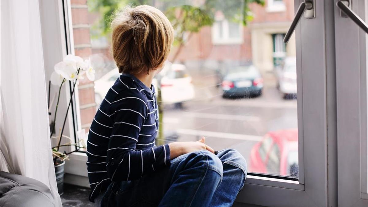 Un niño de siete años mira por la ventana de su casa, en una imagen de recurso.