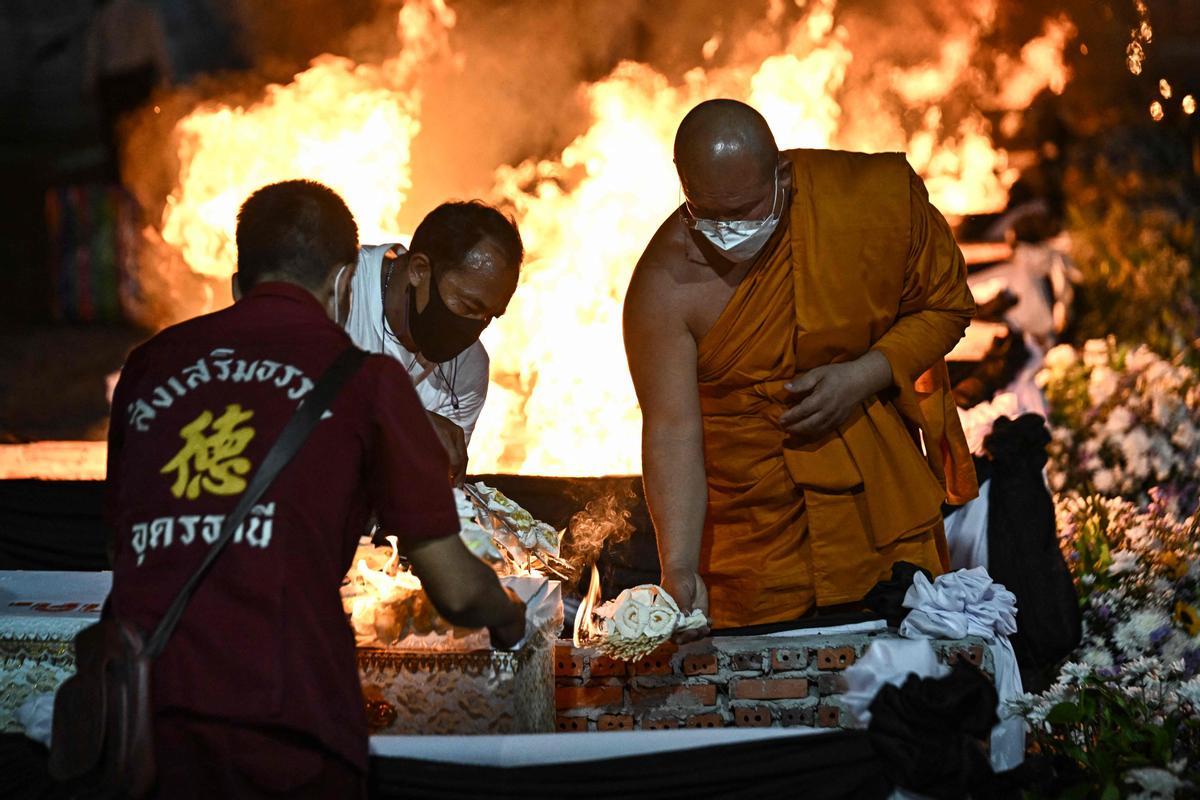 La gente observa cómo las piras funerarias incineran a 19 víctimas del tiroteo en la guardería de Uthai Suwan en el templo Wat Rat Samakee en Uthai Sawan. Un exoficial de policía disparó y mató a 37 personas, al menos 24 de ellos niños, después de irrumpir en una guardería infantil en el noreste de Tailandia.