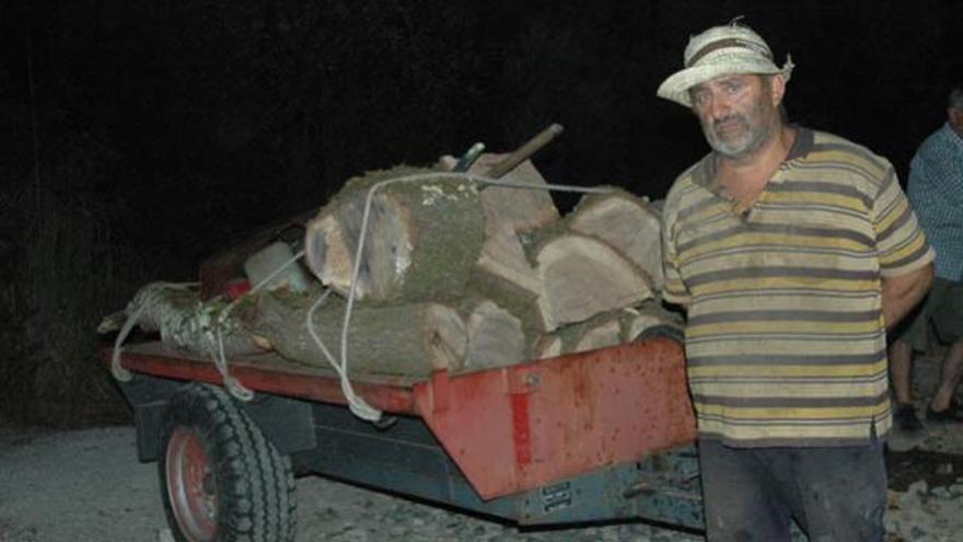 Florencio Pérez, ileso tras el accidente, ante el remolque con leña que transportaba. // J.C.