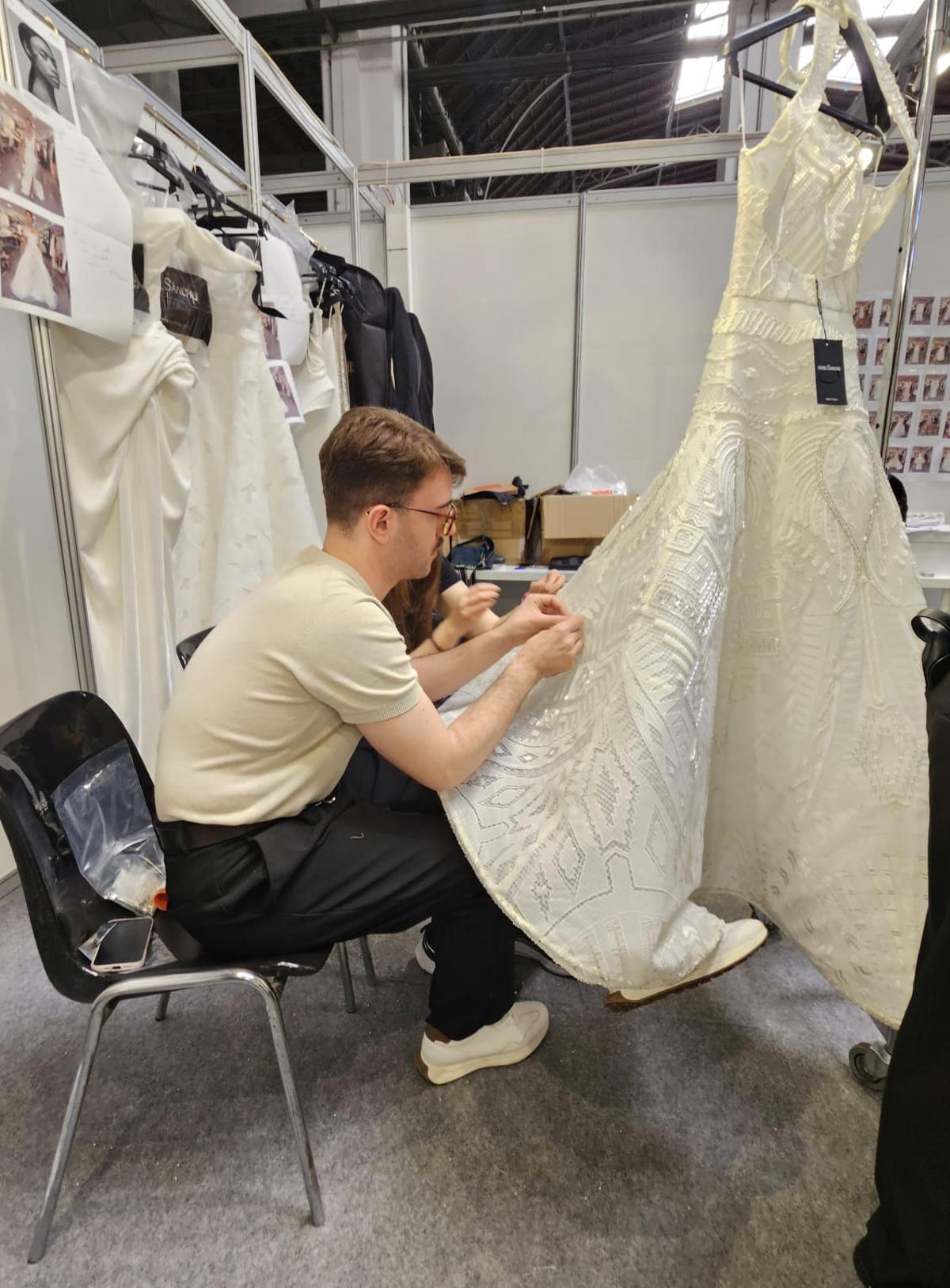 Varios costureros rematan uno de los vestidos-joya, pocas horas antes del desfile de Isabel Sanchís en la Barcelona Bridal Fashion Week.