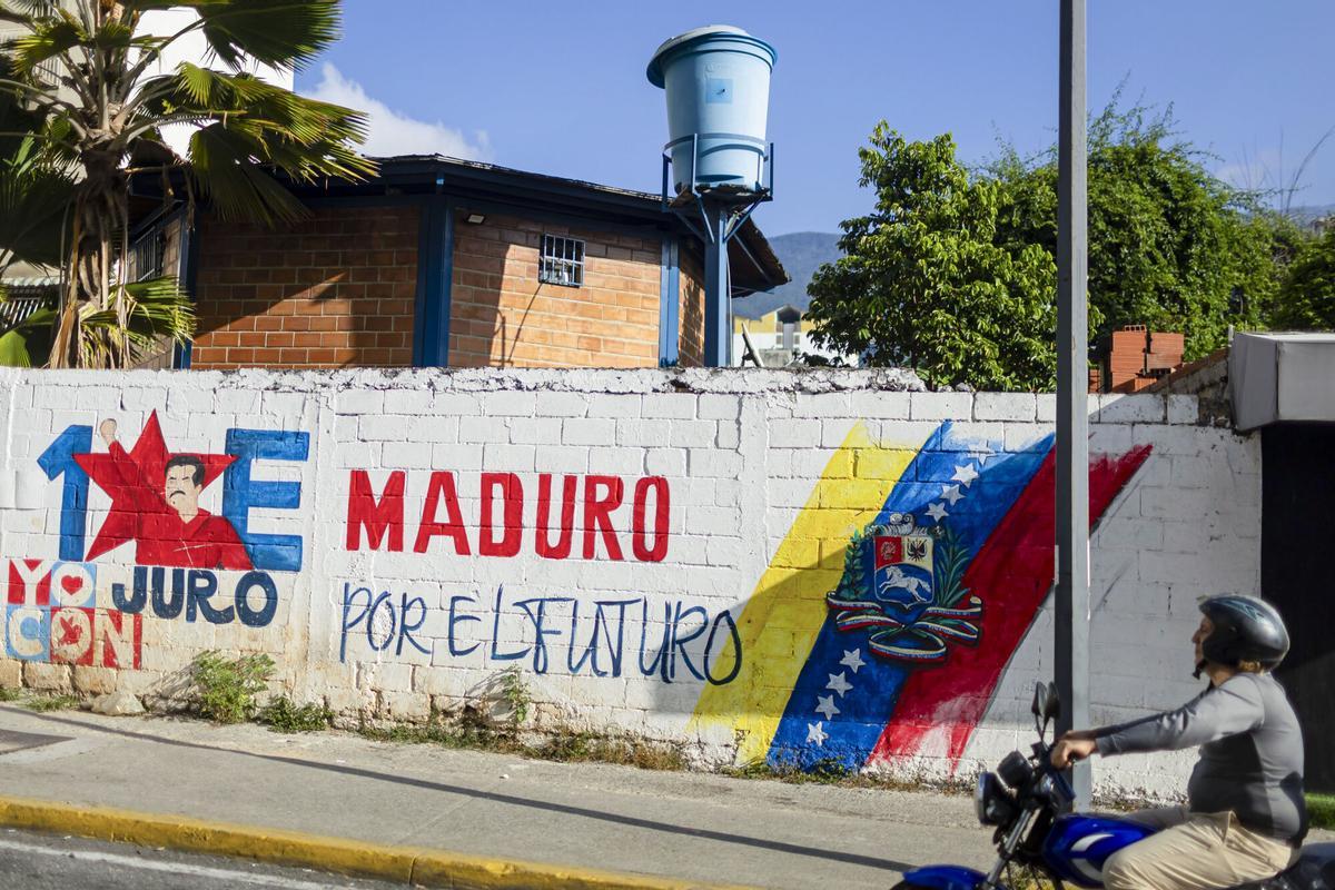 Una persona pasa frente a una pared con un dibujo alusivo al presidente de Venezuela, Nicolás Maduro, este martes en Caracas
