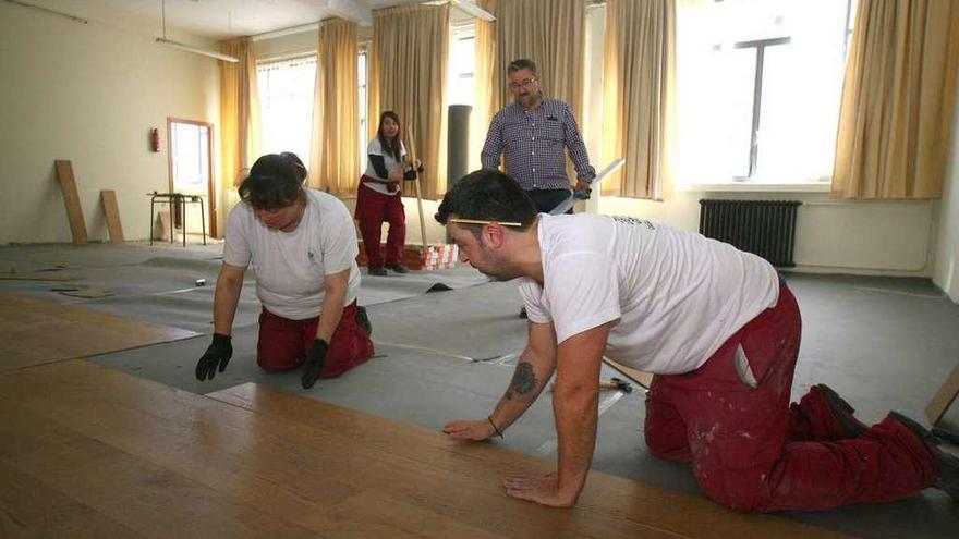 Alumnos-trabajadores del taller de empleo instalando tarima en el local de ensayo.