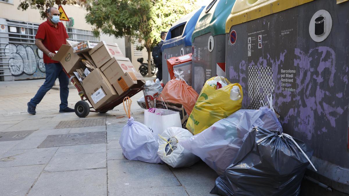 Un hombre trata de reciclar cartón en los contenedores cercanos al Pou de la Figuera