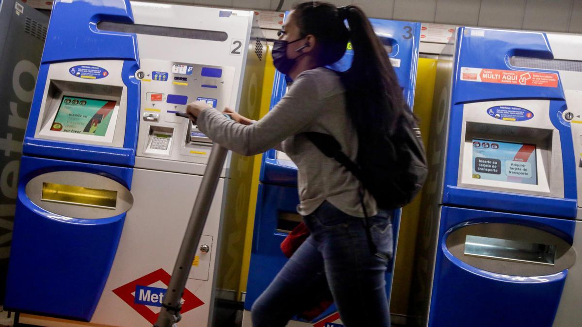 Archivo - Una mujer entra con un patinete eléctrico en el metro