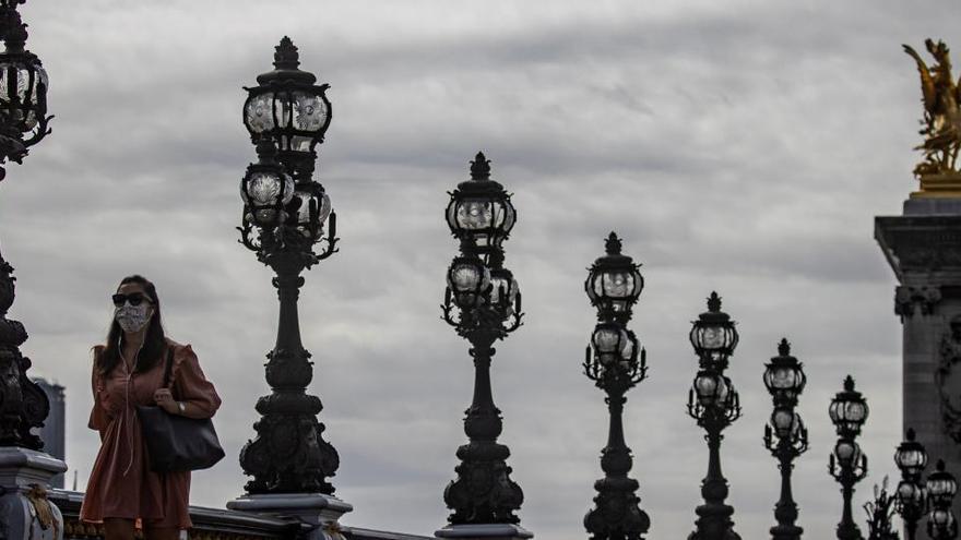 Una mujer camina por el puente Alejandro III de París