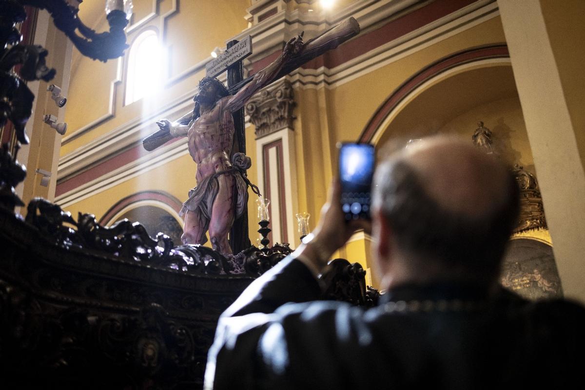Una hombre hace una fotografía con su móvil al un paso de Semana Santa en Zaragoza.