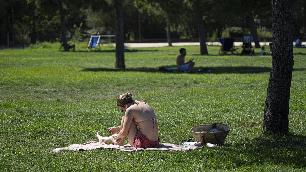 Una joven toma el sol en biquini en el césped de la Clariana de Glòries.