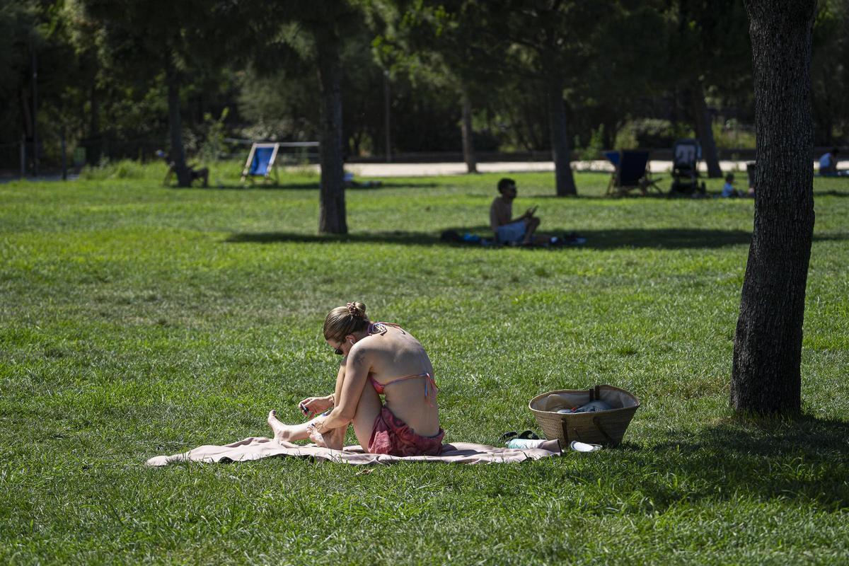 Una joven toma el sol en biquini en el césped en la Clariana de Glòries.