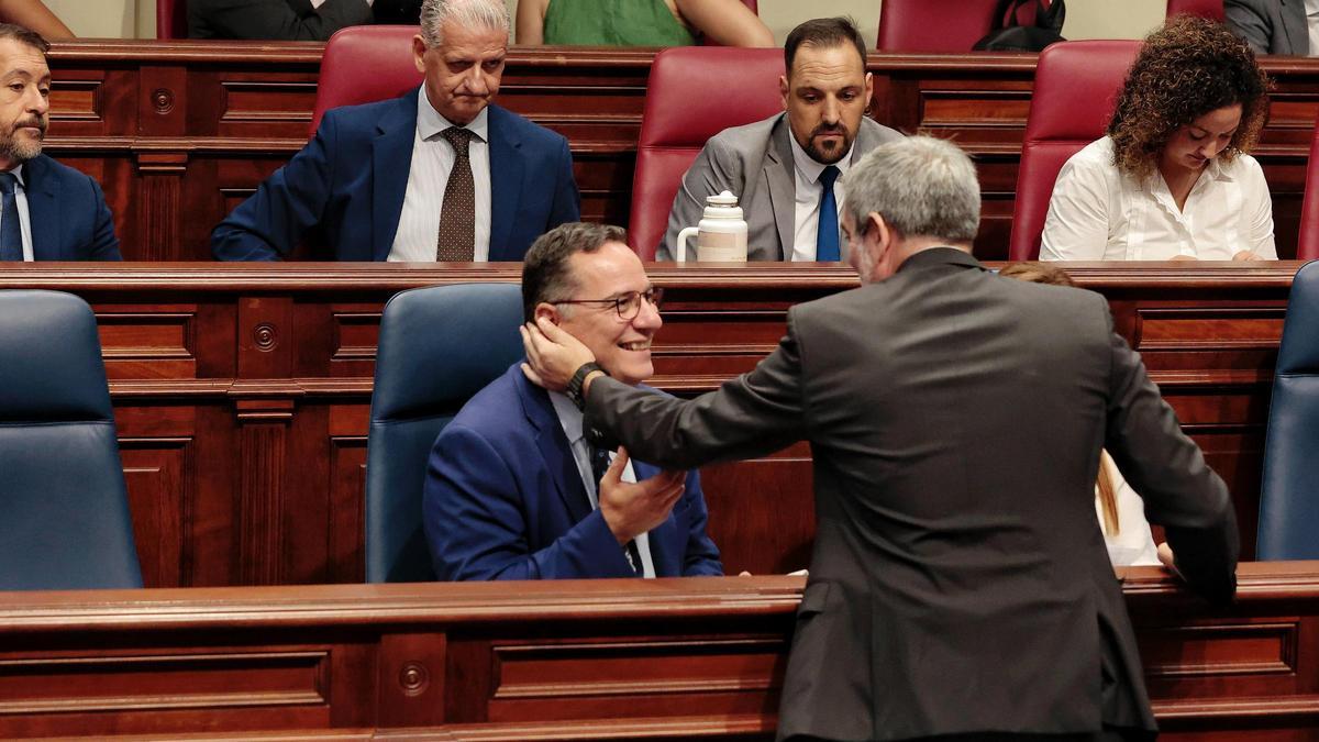 El presidente Fernando Clavijo saluda al consejero de Educación, Poli Suárez, antes de iniciarse la sesión plenaria del Parlamento.