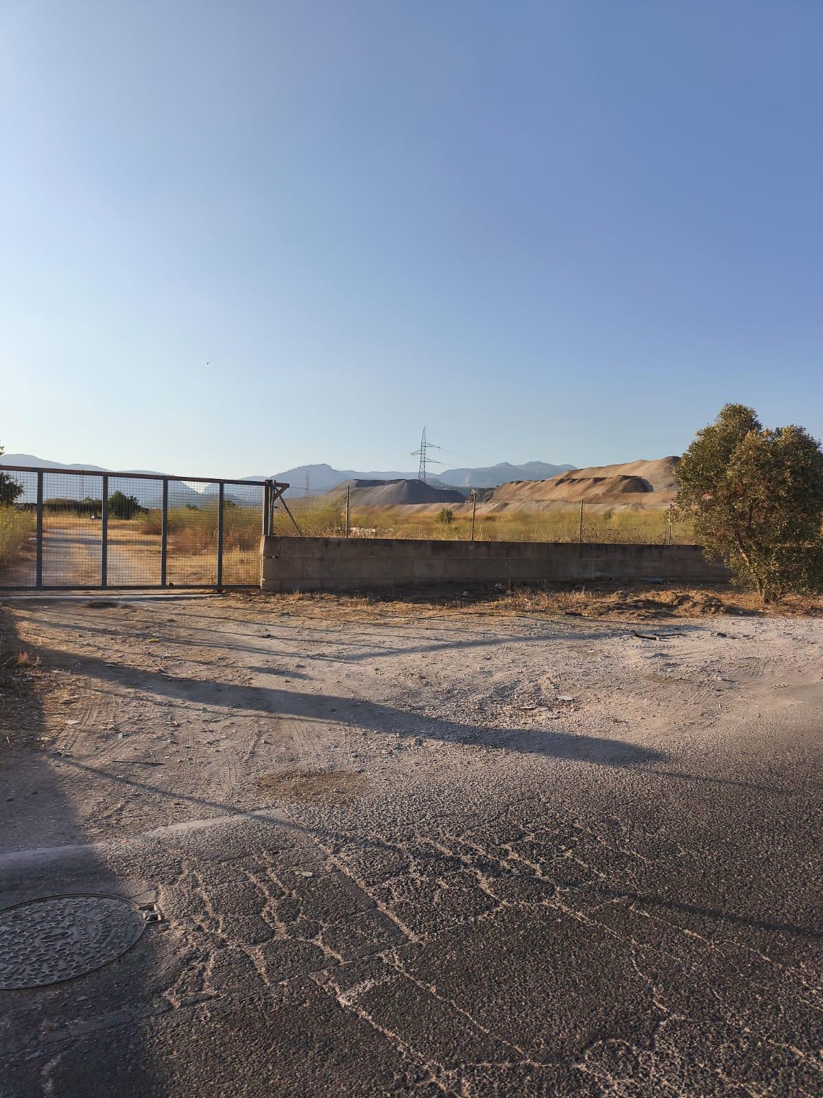 Tras las vallas del recinto, montañas de escoria acumuladas en el exterior de la planta