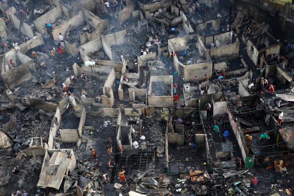 Residentes buscan entre los escombros de sus casas después de que un incendio arrasara una colonia de la ciudad de Quezon, Metro Manila.