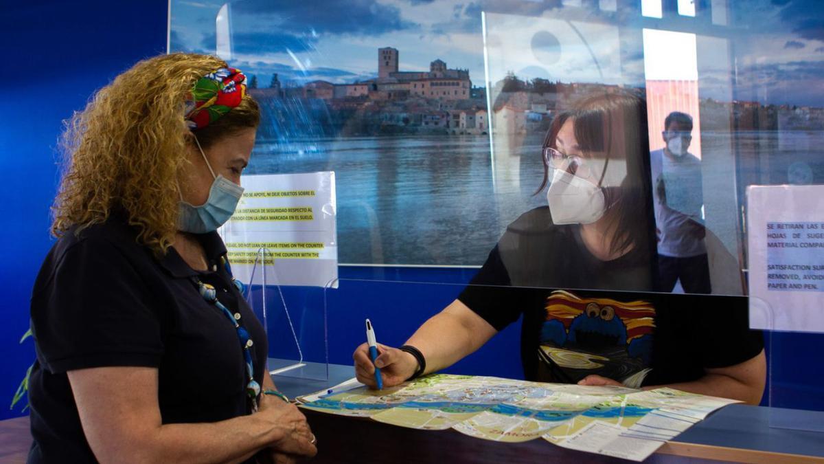 Una mujer recibe información en la oficina de turismo. |