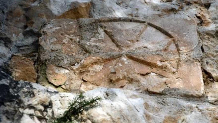 El Purot o penya de l'Alcalà, amb el pantà de Guadalest i Xortà al fons. Baix, a la dreta, la creu de Malta en un mur.