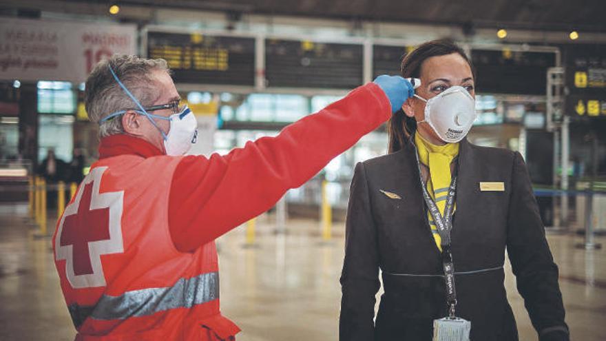Un voluntario de Cruz Roja toma la temperatura a una profesional de Vueling en el aeropuerto de Los Rodeos.
