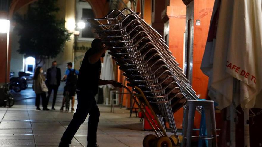 Un camarero recoge la terraza de su bar en Córdoba