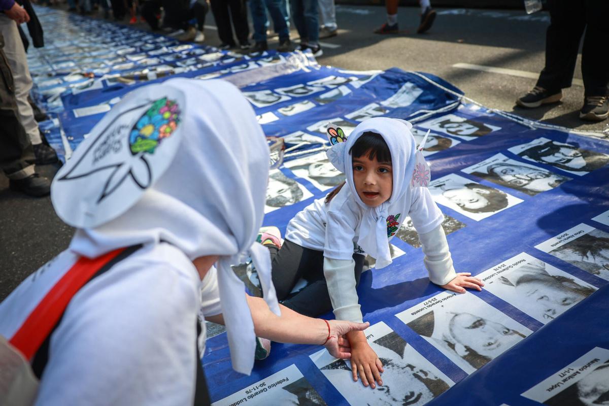 Una mujer y su hija miran las fotografías de desaparecidos en la dictadura argentina, este miércoles en la manifestación de Buenos Aires.