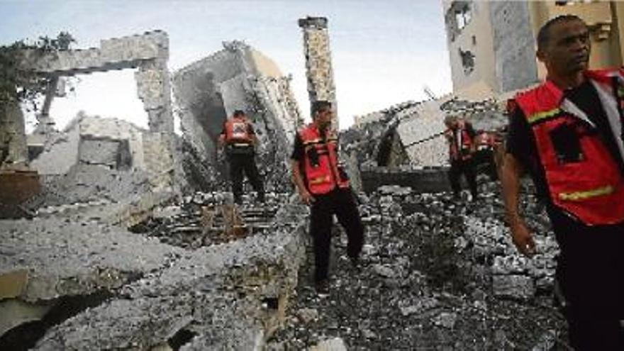 Membres de la Defensa Civil Palestina inspeccionen una torre destruïda pels bombardejos israelians