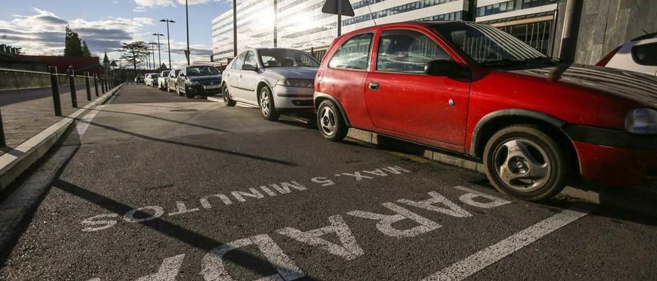 Vehículos mal estacionados sobre la acera, en una calle de parada máxima de cinco minutos.