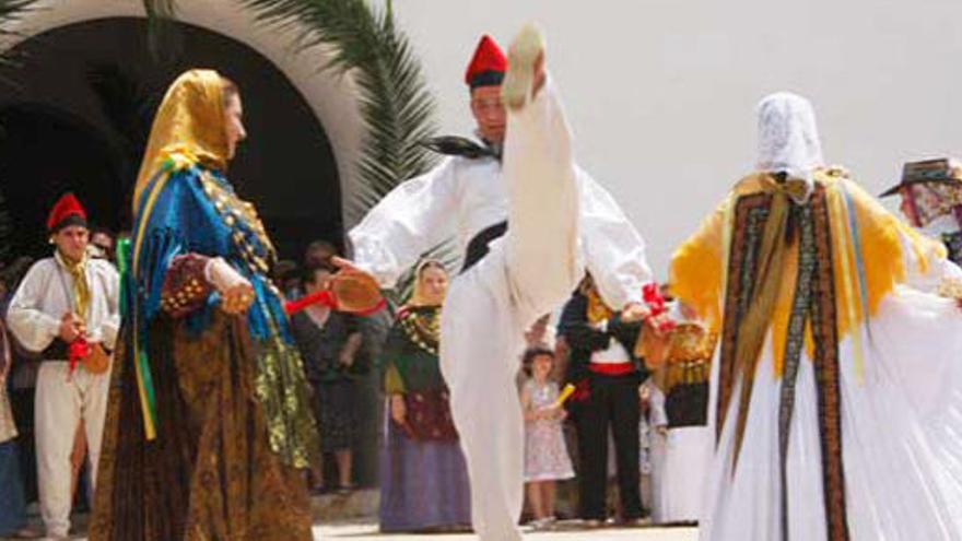 Un joven levanta la pierna por encima de la cabeza de las tres mujeres que bailan con él en la exhibición de danzas tradicionales.