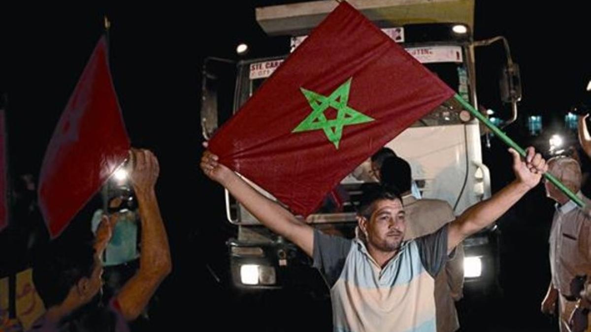 Dos activistas enarbolan banderas marroquís en la frontera de Melilla, el martes por la noche, en plena manifestación de camioneros.