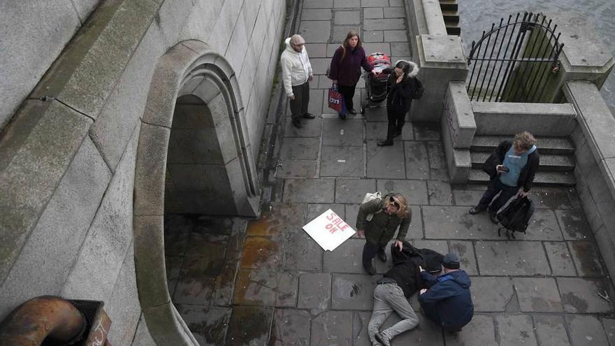 Dos personas atienden a un peatón caído desde la zona alta del puente durante el atropello.