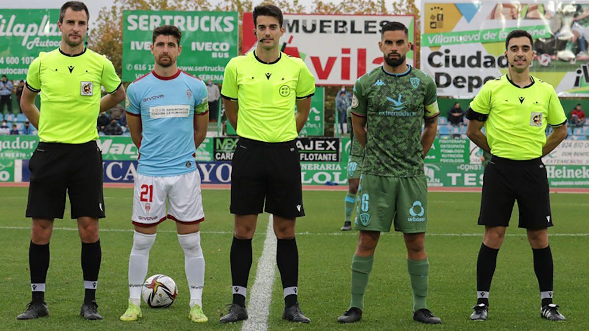 El trío arbitral posa con los capitanes en el Villanovense-Córdoba CF.