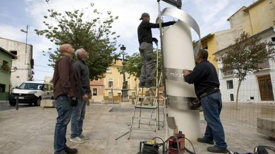 Los autores de la obra, a la izquierda, observan a dos operarios mientras montan la escultura.