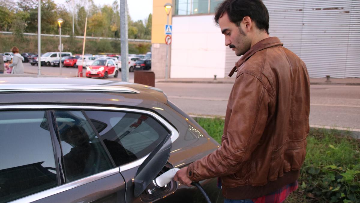 Un home carregant el seu vehicle híbrid a l'únic carregador públic que queda a Girona, davant del Ocines