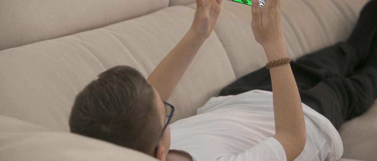 Un adolescente jugando con el teléfono móvil.