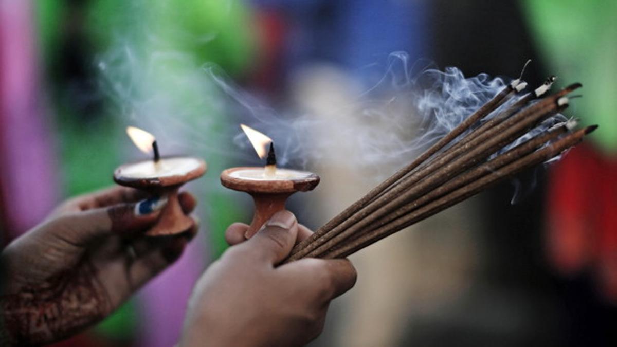 Una mujer nepalí hindú prende incienso al rezar una oración para una vida larga y llena de amor.