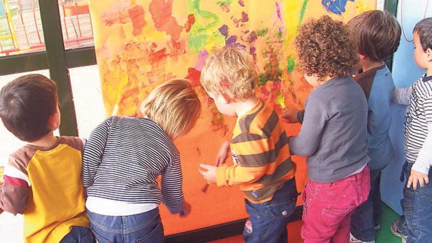 Unos niños pintando un mural en una escuela.  // Eva González