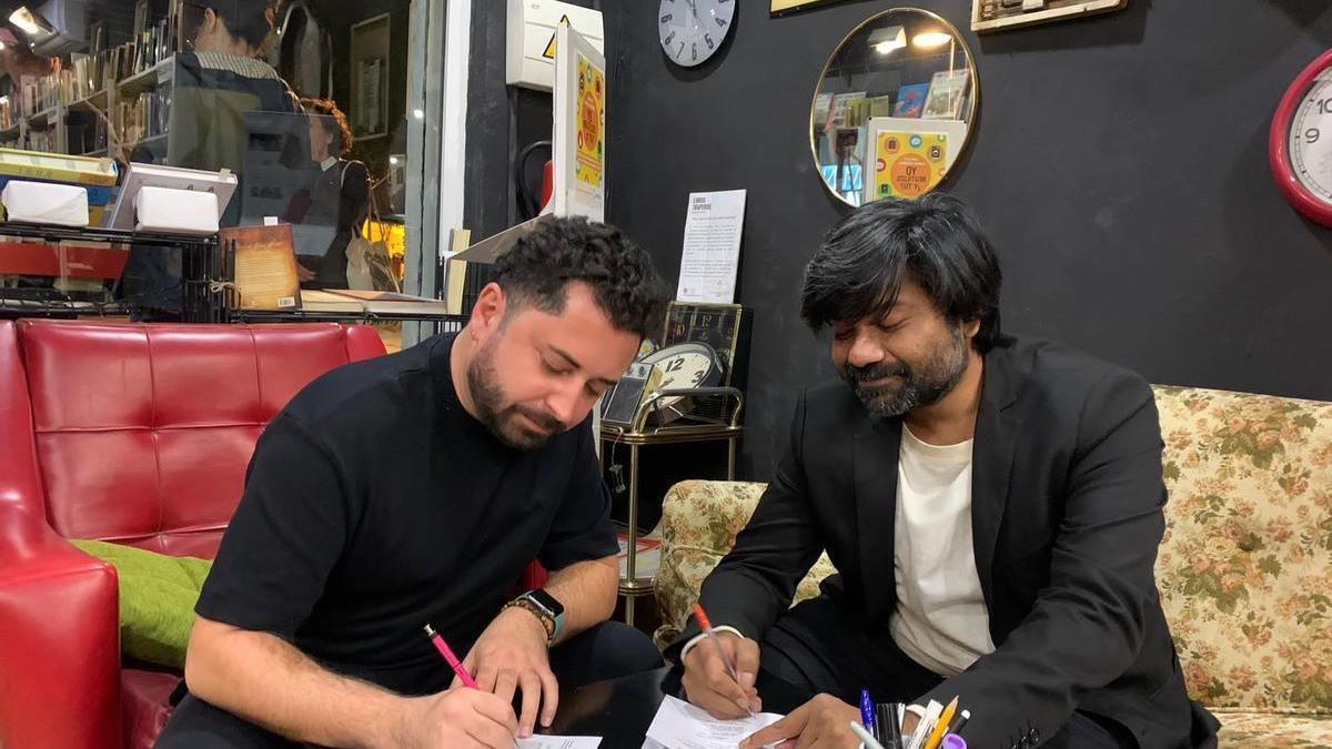 Alberto Soler (i) firma ejemplares de su nuevo cuadernillo junto al  ilustrador Siddharth Gautam Singh.