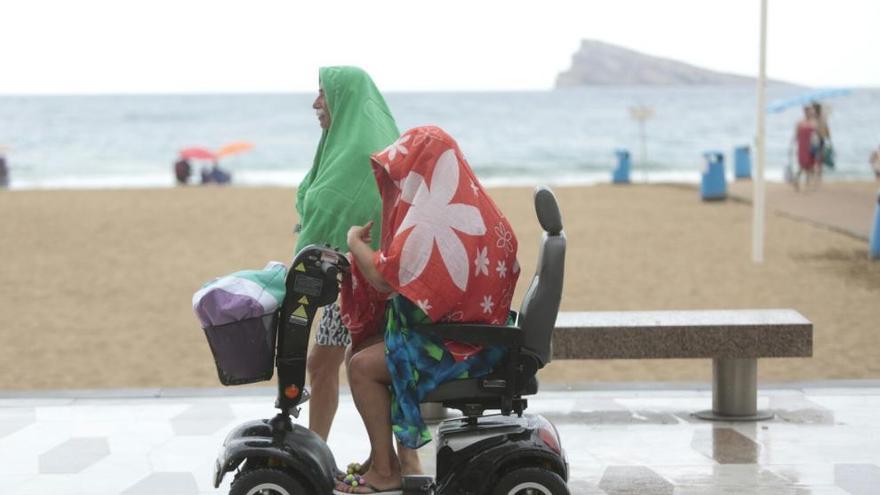 Bañistas protegiéndose del aguacero en la playa en Benidorm