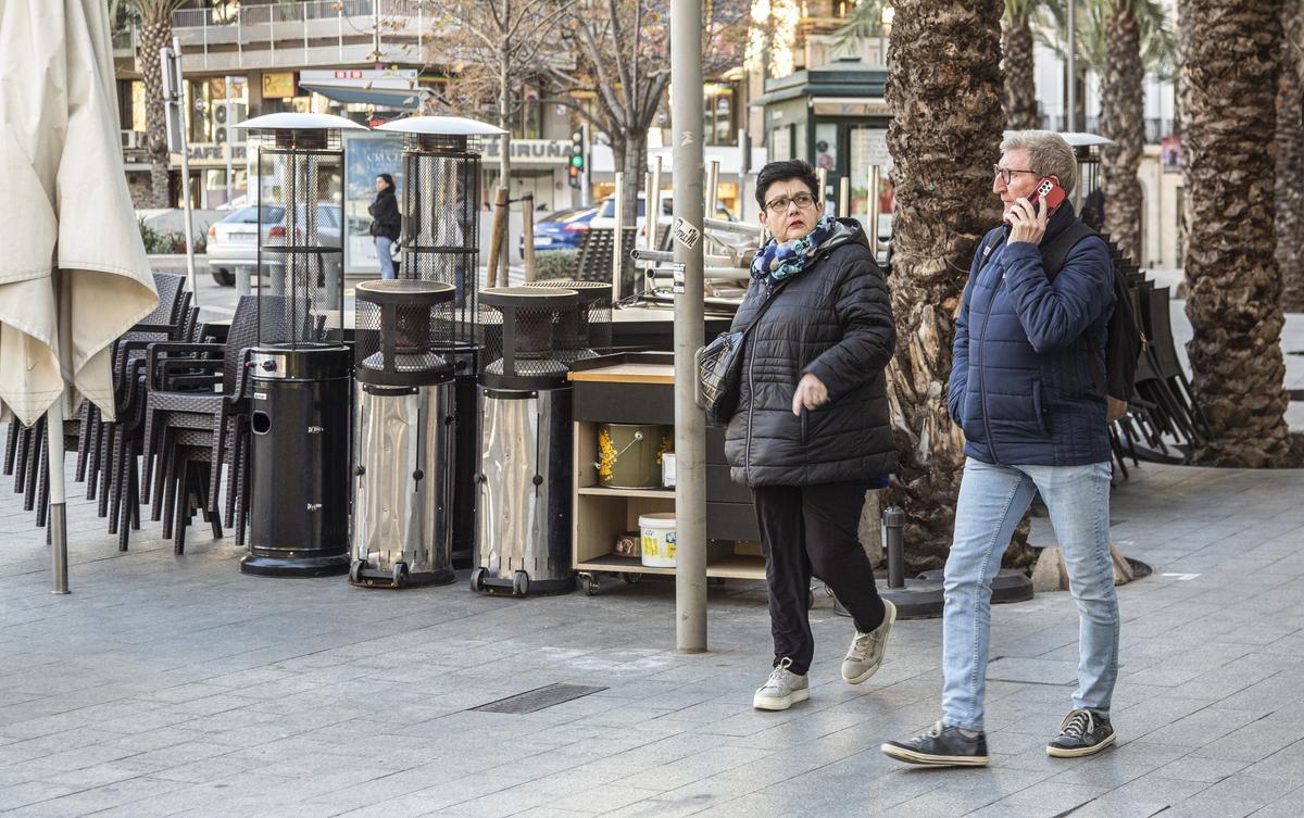 Dos personas pasan junto a una terraza recogida en la plaza de los Luceros, este miércoles.